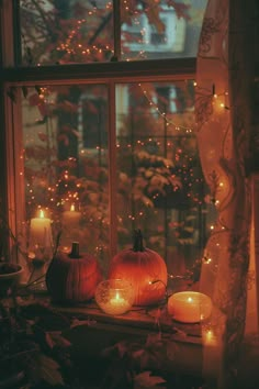 two pumpkins sitting on a window sill with candles