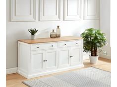 a potted plant sitting on top of a wooden table next to a white wall