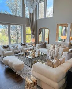 a living room filled with lots of furniture next to large windows on top of a hard wood floor