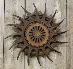 a metal sunburst mounted to the side of a wooden wall with nails sticking out of it