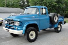 an old blue truck parked in a parking lot