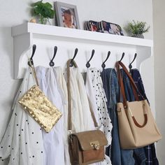 a white coat rack with purses hanging on it