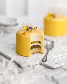 there is a small yellow cake with flowers on it and a spoon next to it