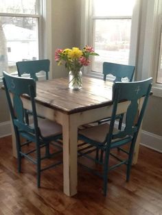 a dining room table with four chairs and a vase of flowers on top of it