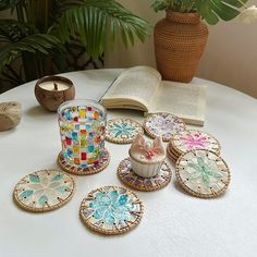 a table topped with lots of plates covered in different colors and designs next to a potted plant