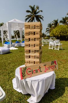 a giant stack of wooden blocks sitting on top of a lush green field next to palm trees