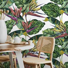 a table with two chairs and a vase on it in front of a tropical wallpaper