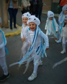 several children in costumes are walking down the street with blue streamers on their heads