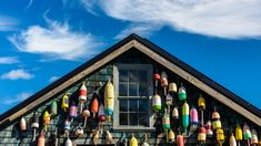 a building with lots of different colored buoys hanging from it's roof and windows