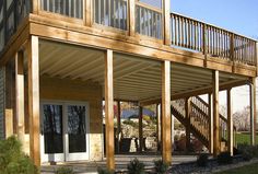 a large wooden deck with stairs leading up to the front door and back porch area