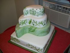 a white cake with green designs on it sitting on top of a red tablecloth