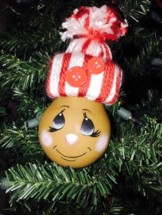 an ornament hanging from a christmas tree with a smiley face on it's head