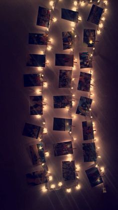 some lights are hanging on the wall with pictures attached to it and string lights strung from them