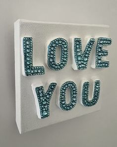 the words love you are made out of white paper and blue beads on top of each other