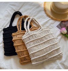 three straw bags sitting on top of a white bed next to a hat and flowers