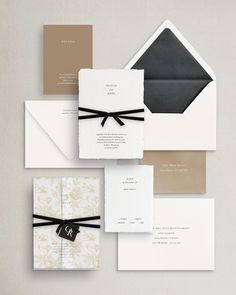 the wedding stationery is laid out on top of each other and tied with black ribbon