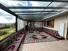 a room with many rugs on the floor and windows above it that look out onto a green field