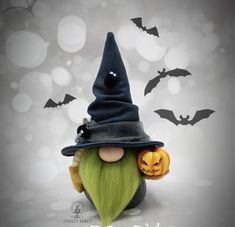 a green haired wizard doll wearing a black hat and holding a jack - o'- lantern