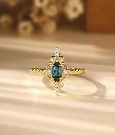 a gold ring with an oval blue topazte surrounded by small white and clear stones