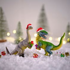 two toy dinosaurs are in the snow with presents