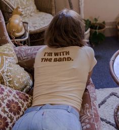 a woman sitting on top of a couch wearing a t - shirt that says i'm with the band