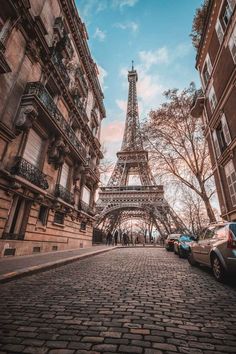 the eiffel tower in paris, france with cars parked on the side walk