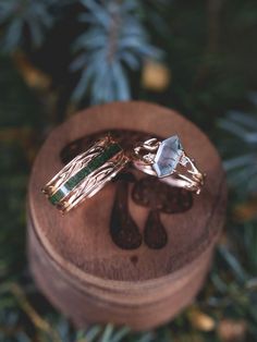 A matching wedding ring set from Staghead Designs sits on a custom mushroom engraved ring box. These rings in our "Artemis" designs include a 14K rose gold wedding band that has antler/branch-like metal work & a centered moss inlay. On the right is the "Artemis" engagement ring with an antler/branch-like 14K rose gold band, diamond accents, & an elongated hexagon cut moss agate center stone. These rings can also be made in white or yellow gold & with a variety of unique stones & inlay materials. Moss Agate Wedding Rings, Whiskey Barrel Wedding Ring, Antler Wedding Rings, Matching Wedding Ring Sets, Nature Wedding Ring, His And Her Wedding Rings, Agate Wedding Ring, Nontraditional Engagement Rings, Engagement Rings Wedding Bands Set