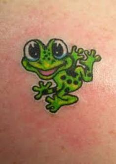 a green frog tattoo on the back of a woman's shoulder