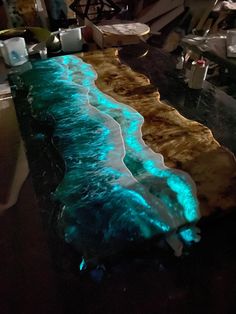 a table that has some blue and green water on it with lights in the background