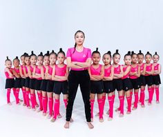 a woman standing in front of a group of girls wearing pink shirts and black shorts