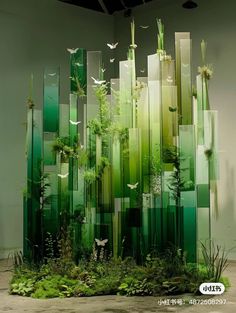 an art installation made out of green glass blocks and plants with birds flying over them