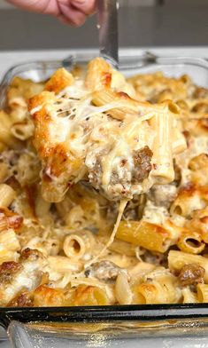 a person is scooping some food out of a casserole dish with cheese