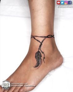 a tattoo on the foot of a person with a small feather attached to it's ankle