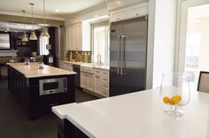 a modern kitchen with an island and stainless steel appliances in the center, along with white countertops