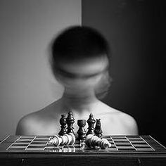 a man standing in front of a chess board with his head turned to the side