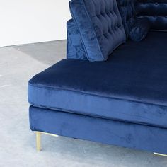 a blue couch with pillows on it in a room that is white and has concrete floors