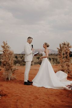 a bride and groom standing in the desert with their wedding vows held by each other