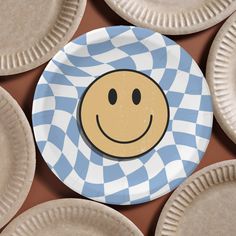 a blue and white plate with a smiley face on it surrounded by paper plates that are lined up in rows