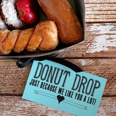 donuts and pastries in a box on a wooden table with a sign that says, donut drop just because we like you a lot