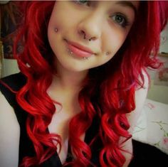 a woman with red hair and piercings on her nose