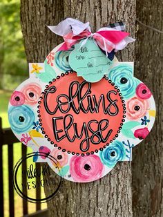 a wreath with the words ellen's ely hanging on a tree in front of a fence