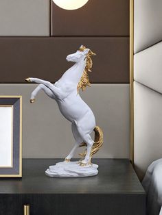 a white horse statue sitting on top of a wooden table next to a framed photo