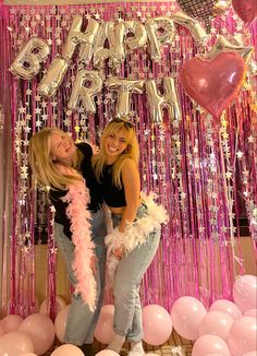 two girls standing in front of balloons and streamers with the words happy birthday on it