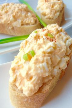 two white plates with food on them and some green onions in the middle one is topped with mayonnaise