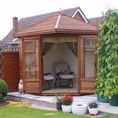 a wooden gazebo sitting in the middle of a yard next to flowers and plants