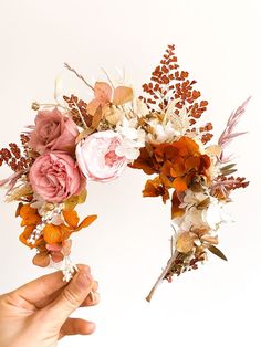 two hands holding flowers in front of a white background