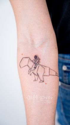 a person with a tattoo on their arm that has a drawing of a man riding an origami horse