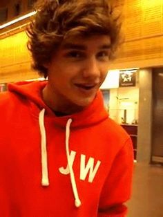 a young man with curly hair wearing a red hoodie