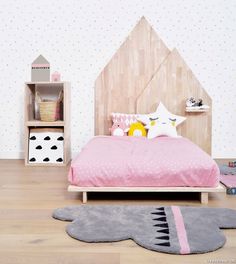 a child's bedroom with pink bedding and wooden headboard on the wall