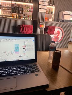 an open laptop computer sitting on top of a wooden table next to a soda bottle